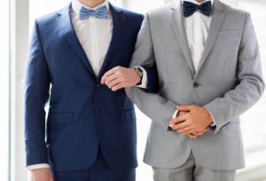 people, homosexuality, same-sex marriage and love concept - close up of happy male gay couple holding hands on wedding