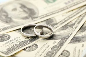 Silver wedding rings on one hundred dollars bill background representing finances when getting married