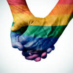 gay couple holding rainbow colored hands