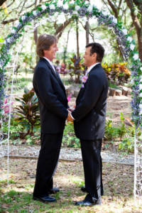 gay couple being married under arch