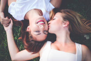 Overhead of young women smiling lying on the grass.