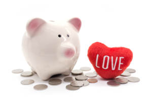 Piggy bank and love heart plush surrounded by coins representing how to cut your wedding costs