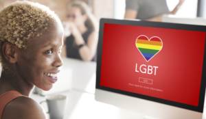 transgender women of color looking a a rainbow lgbt heart on a computer screen