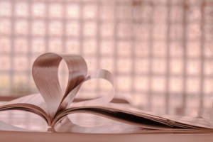 A book with pages tucked into a heart representing choosing readings for your ceremony.