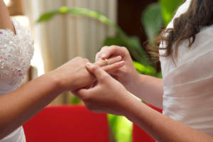 Two brides exchanging wedding rings. pick a wedding officiant