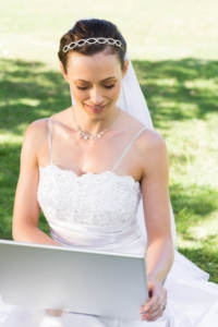 Bride looking at her wedding website on a laptop in a garden