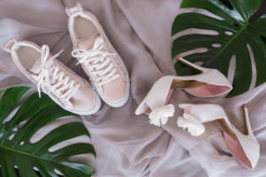 A pair of comfortable sneakers next to some pink high heels