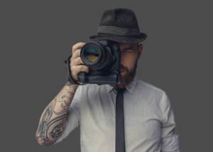 Wedding photographer with tattoos holding a camera up to their eye