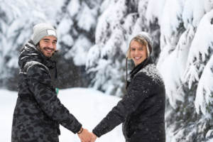 A gay couple holding hands while walking in the snow on a winter date