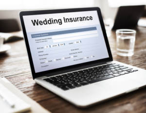 A laptop on a table opened to a screen that shows wedding insurance