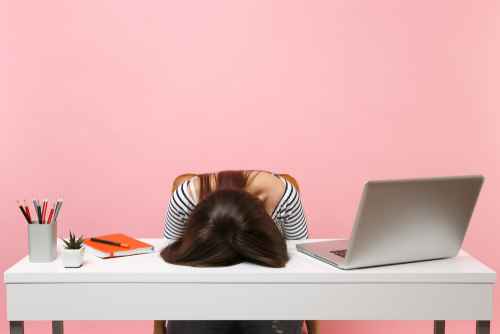 A woman with her head on a desk feeling stress and needing healthy ways to handle it