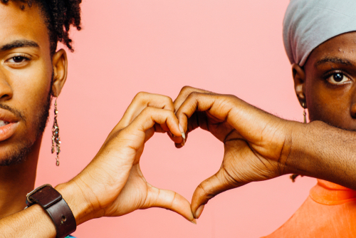 Gay black couple making a hand heart together while developing emotional intimacy