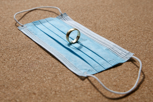 A wedding ring balanced on top of a mask