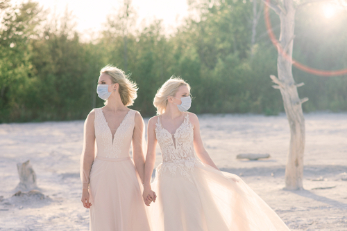 A wedding during COVID with two brides wearing masks.