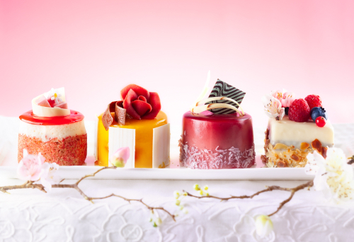 Various mini wedding cakes on a white plate. Sweets decorated with fresh berries and flowers for holiday.