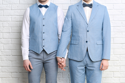 A gay couple holding hands in their wedding outfits considering reasons to change