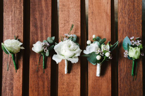 5 boutonniere examples on wood boards.