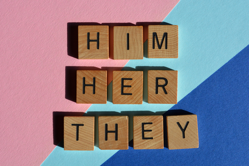 him, her, and they on wood blocks representing pronoun terms to be mindful of.