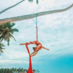 performance artist at same-sex wedding reception hanging from red cloth