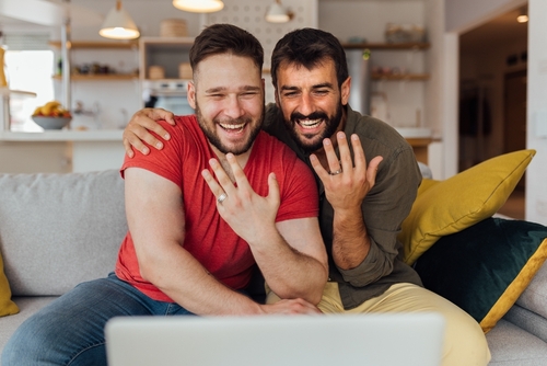 Same-sex couple celebrating their engagement over a video call.