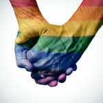 Close-up of gay couple holding hands in rainbow pattern