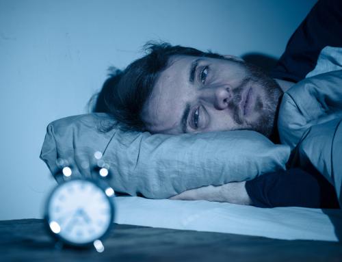 Man trying to get better rest looking at an alarm clock