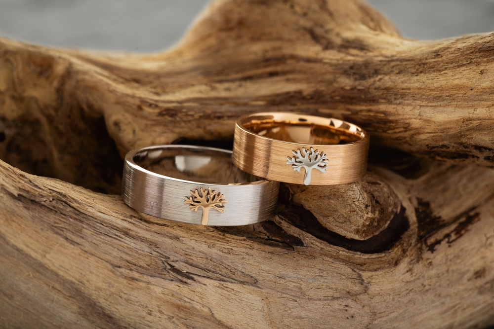 Wedding bands with tree designs on a piece of wood for an eco-friendly wedding