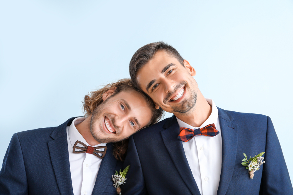 gay couple smiling at a good guest at their wedding