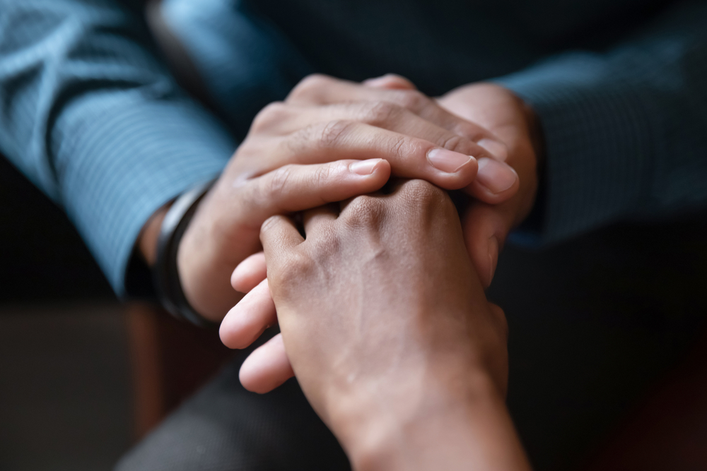 Two people holding hands to comfort a partner who is transitioning