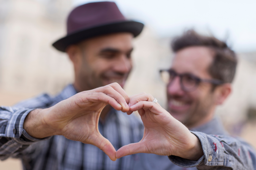 Same-sex couple making a heart with their hands while discussing date night ideas
