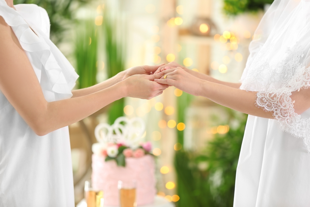 Two brides holding hands during their small wedding reception.