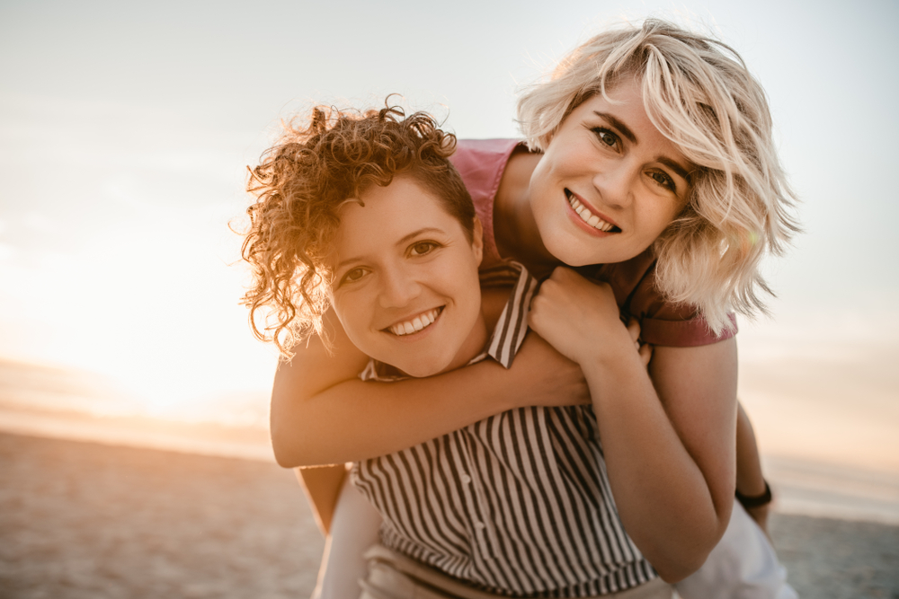 A lesbian couple carrying one person on piggyback. Skills same-sex couples can use to improve their relationship